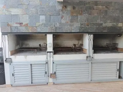 a store front with white doors and a stone wall at Apartamento Carlos Paz in Villa Carlos Paz