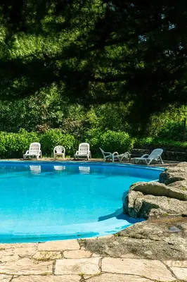 a swimming pool with two lawn chairs and chairs at Hotel Las Cascadas in La Cumbrecita