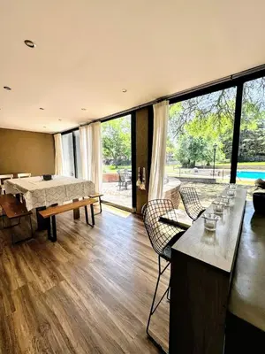 a living room with a table and chairs and a large window at Casa Las Magnolias Villa General Belgrano in Villa General Belgrano