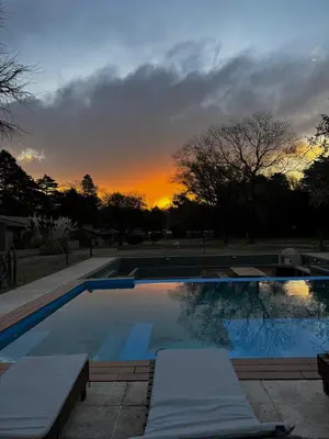 a swimming pool with a sunset in the background at Casa Las Magnolias Villa General Belgrano in Villa General Belgrano