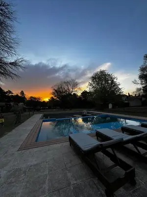 a swimming pool with a sunset in the background at Casa Las Magnolias Villa General Belgrano in Villa General Belgrano