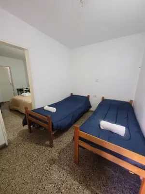 two beds with blue sheets in a room at Hotel Belgrano in Villa Carlos Paz
