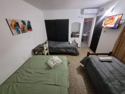 a small room with two beds and a couch at Hotel Belgrano in Villa Carlos Paz