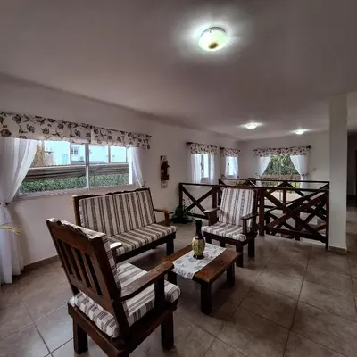a living room with chairs and a table and windows at Posada Yumei in Villa General Belgrano