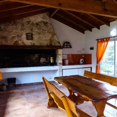 a dining room with a wooden table and a kitchen at Posada Yumei in Villa General Belgrano