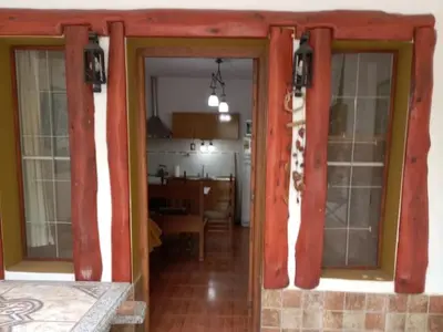 a living room with red curtains and a kitchen at Aldea Granpas in Embalse