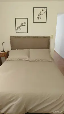 a bedroom with a large white bed with two pictures on the wall at Makipura in Cordoba