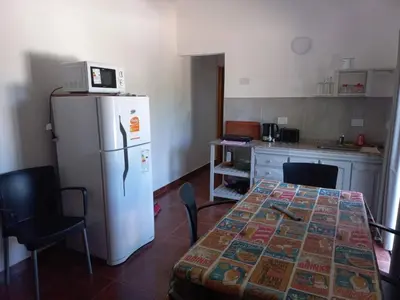 a kitchen with a table and a white refrigerator at Chalets de la paix in Santa Rosa de Calamuchita