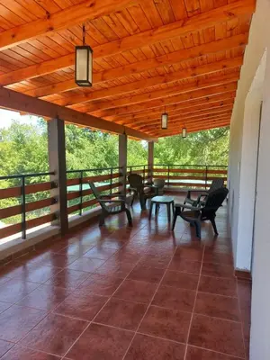 a porch with chairs and a table and a wooden ceiling at Chalets de la paix in Santa Rosa de Calamuchita