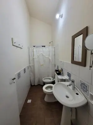a white bathroom with two toilets and a sink at Doña Vanina in Villa Larca