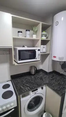 a small kitchen with a microwave and a washing machine at Opera Villa Carlos Paz- Moderno - exclusivo- La mejor ubicación in Villa Carlos Paz