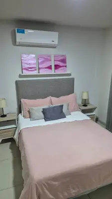 a bedroom with a large bed with pink sheets and pillows at Opera Villa Carlos Paz- Moderno - exclusivo- La mejor ubicación in Villa Carlos Paz