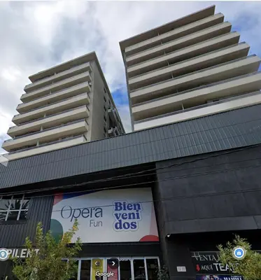 a building with a sign in front of two tall buildings at Opera Villa Carlos Paz- Moderno - exclusivo- La mejor ubicación in Villa Carlos Paz