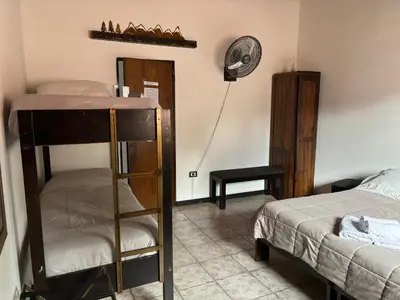 a bedroom with a bunk bed and a room with a fan at Cucu Haus Hostel in La Cumbrecita