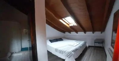 a bedroom with a white bed with a skylight at Cucu Haus Hostel in La Cumbrecita