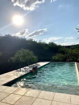 two people in a swimming pool with the sun in the sky at Casa de campo in Villa San Nicolás