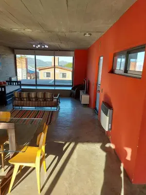 a living room with orange walls and a yellow chair at SARA HOUSE LARGE in Santa Rosa de Calamuchita