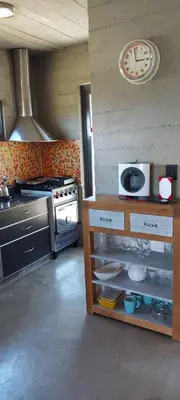 a kitchen with a stove and a clock on the wall at SARA HOUSE LARGE in Santa Rosa de Calamuchita