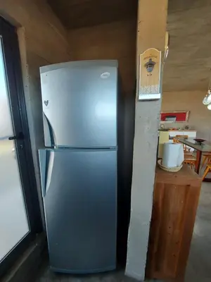 a stainless steel refrigerator in a kitchen next to a table at SARA HOUSE LARGE in Santa Rosa de Calamuchita
