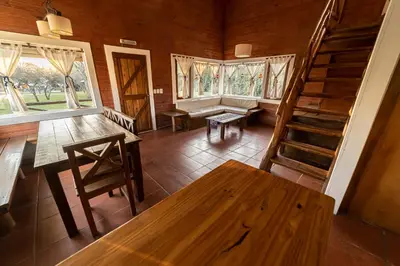 a room with a table and a bench and windows at Cabañas Cuatro Horizontes in Villa General Belgrano