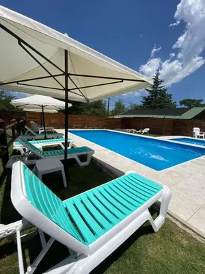 a pool with two lounge chairs and an umbrella at Cabañas Cuatro Horizontes in Villa General Belgrano