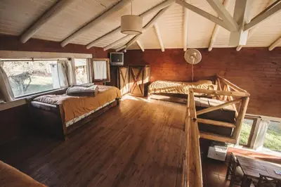 a room with two beds and a table and windows at Cabañas Cuatro Horizontes in Villa General Belgrano