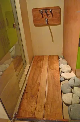 a room with a shower with a wooden floor and rocks at Cañas Suites Urbanas in Mina Clavero