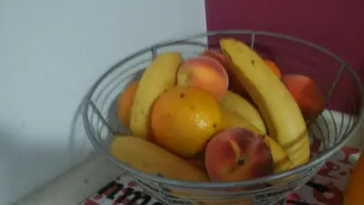 a bowl of fruit with bananas apples and oranges at Cañas Suites Urbanas in Mina Clavero