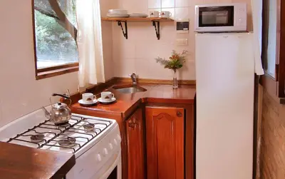 a kitchen with a stove and a white refrigerator at Aldea de los Pajaros in Villa General Belgrano