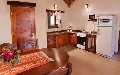a kitchen with a wooden table and a white refrigerator at Aldea de los Pajaros in Villa General Belgrano