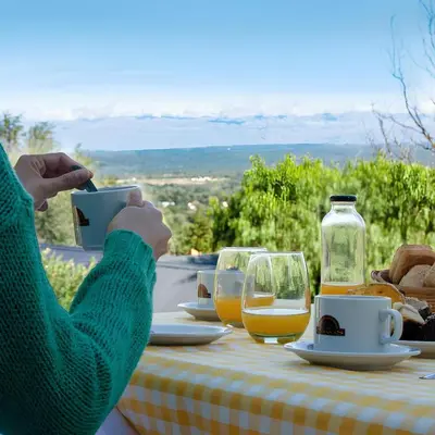a person holding a cell phone at a table with drinks at Aldea de los Pajaros in Villa General Belgrano