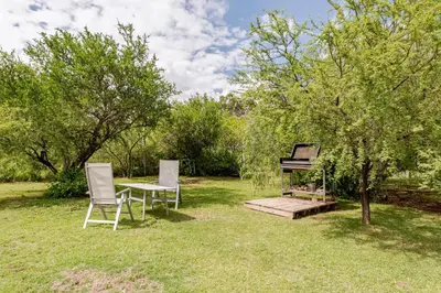 two chairs and a table and a piano in a yard at Cabañas con jacuzzi privado y vistas al cerro Champaquí in San Javier
