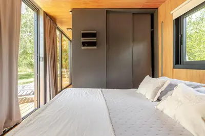 a bedroom with a large bed and a large window at Cabañas con jacuzzi privado y vistas al cerro Champaquí in San Javier