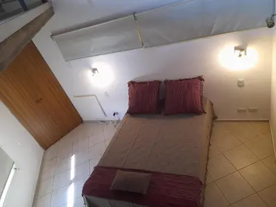 a large bed in a room with two red pillows at LA PEDRERA - VILLA DEL LAGO - Carlos Paz - Córdoba - Argentina in Villa Carlos Paz