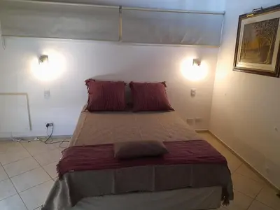 a bedroom with a large bed with two red pillows at LA PEDRERA - VILLA DEL LAGO - Carlos Paz - Córdoba - Argentina in Villa Carlos Paz