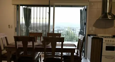 a kitchen with a table and chairs and a balcony at LA PEDRERA - VILLA DEL LAGO - Carlos Paz - Córdoba - Argentina in Villa Carlos Paz