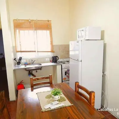 a kitchen with a wooden table and a white refrigerator at La Serafina in Los Reartes
