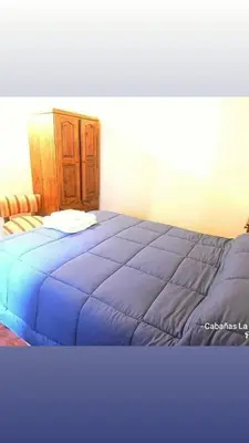 a bedroom with a blue bed with a wooden cabinet at La Serafina in Los Reartes