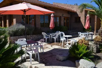 a patio with tables and chairs and an umbrella at Colina del Valle in Mina Clavero
