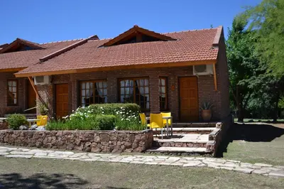 a brick house with yellow chairs in front of it at Colina del Valle in Mina Clavero
