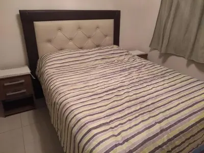 a bed with a striped comforter in a bedroom at Departamento en Nueva Córdoba - Patagonia 7 in Cordoba