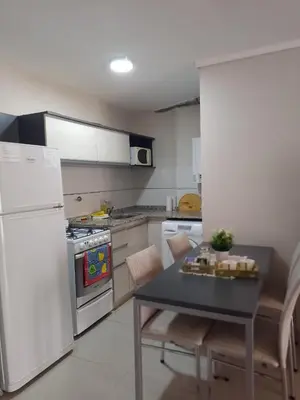 a kitchen with a table and a white refrigerator at Departamento en Nueva Córdoba - Patagonia 7 in Cordoba