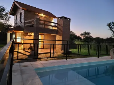 a house with a swimming pool in front of a house at Cabañas San Pío in Merlo
