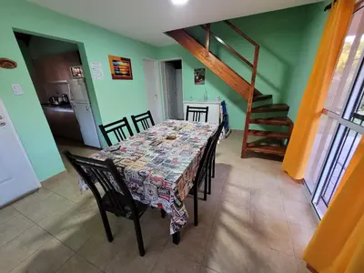 a dining room with a table and chairs and a staircase at Cabañas San Pío in Merlo