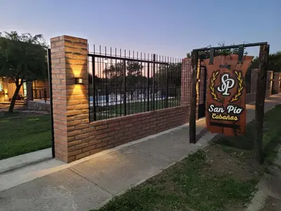 a gate with a sign in front of a brick fence at Cabañas San Pío in Merlo