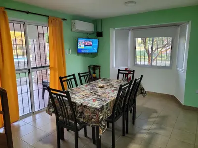 a dining room with a table and chairs and a television at Cabañas San Pío in Merlo