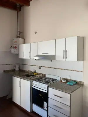 a kitchen with white cabinets and a stove top oven at Departamentos Monteolivos in Merlo