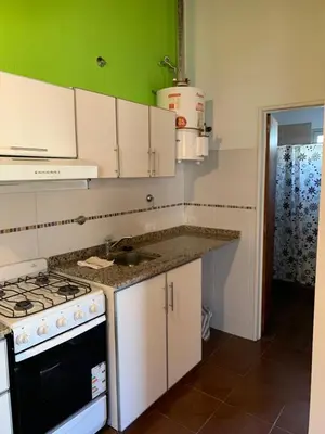 a kitchen with white cabinets and a stove top oven at Departamentos Monteolivos in Merlo