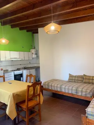 a kitchen with a table and a bed in a room at Departamentos Monteolivos in Merlo