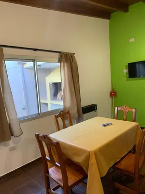 a dining room with a table and chairs and a window at Departamentos Monteolivos in Merlo